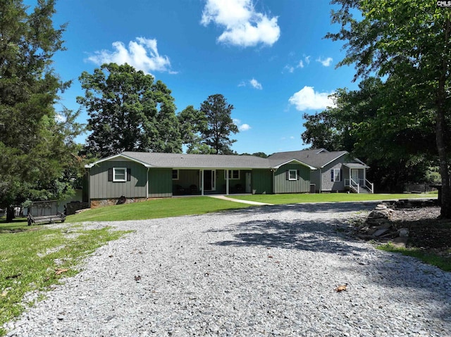 ranch-style house with gravel driveway and a front lawn