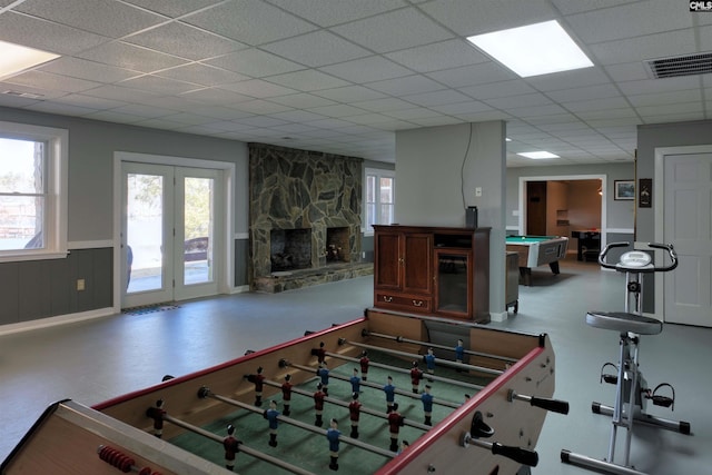 recreation room with wainscoting, pool table, a drop ceiling, and a stone fireplace