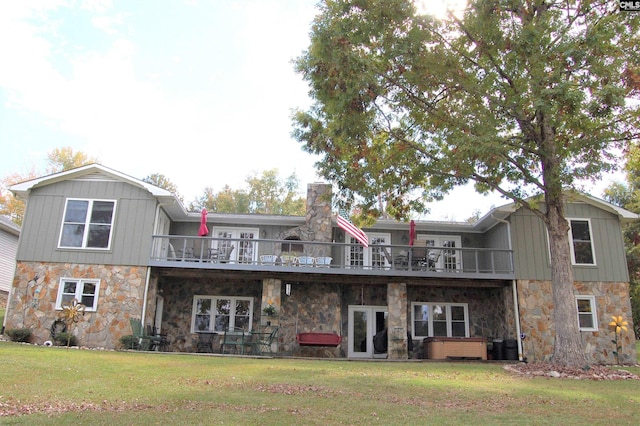 rear view of house with stone siding, a hot tub, a chimney, and a yard