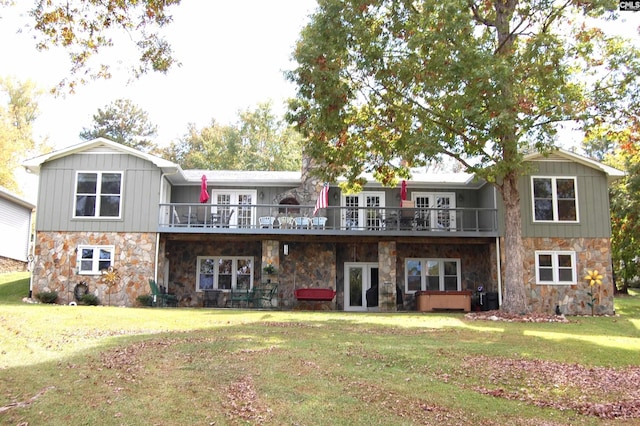 back of property with a yard, stone siding, and french doors