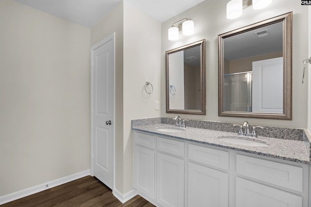 full bathroom with baseboards, wood finished floors, a sink, and double vanity