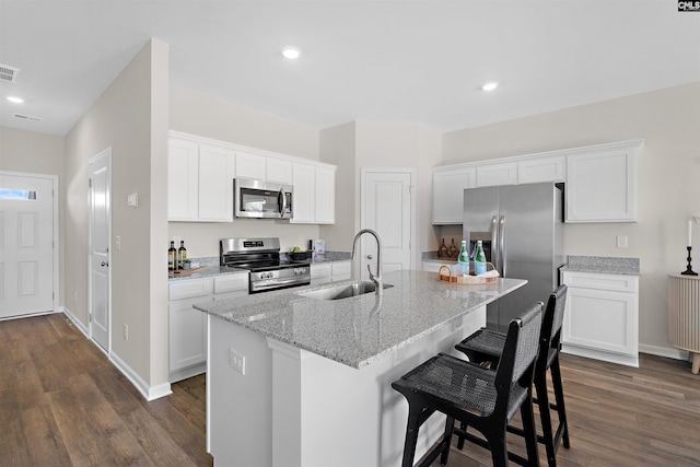 kitchen featuring a sink, a breakfast bar area, appliances with stainless steel finishes, dark wood-style flooring, and visible vents