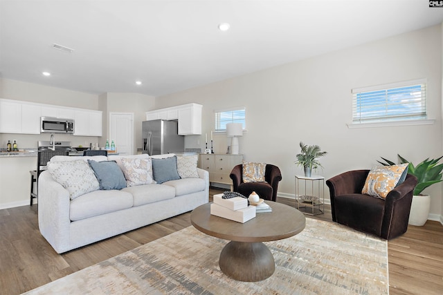 living area featuring baseboards, wood finished floors, visible vents, and recessed lighting