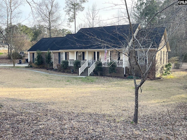 view of front of home with a porch, a front lawn, and brick siding