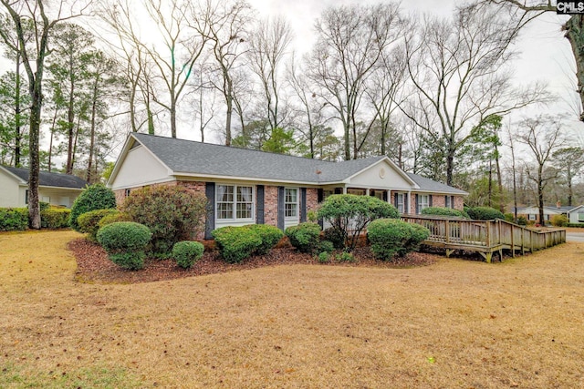 ranch-style home featuring a front lawn, a wooden deck, and brick siding