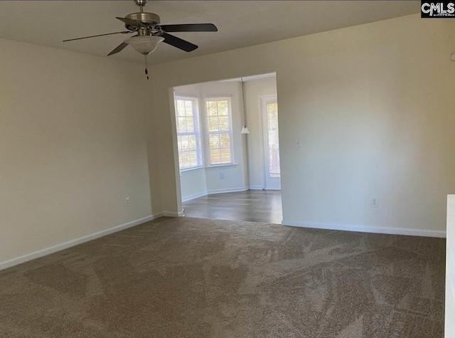 empty room featuring ceiling fan, dark colored carpet, and baseboards