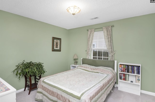 bedroom with a textured ceiling, baseboards, visible vents, and light colored carpet