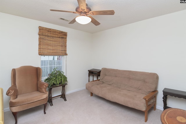 sitting room with a ceiling fan, visible vents, a textured ceiling, and light colored carpet