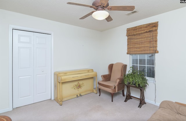 sitting room with baseboards, carpet, a ceiling fan, and a textured ceiling