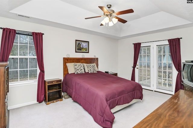 bedroom with light carpet, visible vents, access to exterior, multiple windows, and a raised ceiling