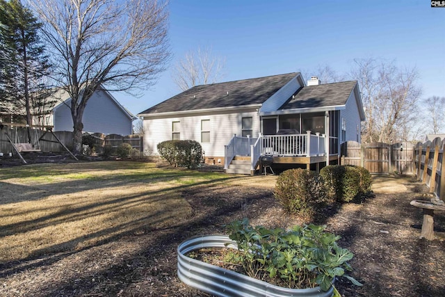 view of front of home featuring a front yard, a fenced backyard, a chimney, and a wooden deck