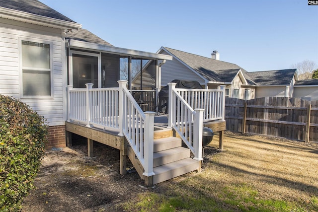 wooden terrace featuring a sunroom, fence, and a yard
