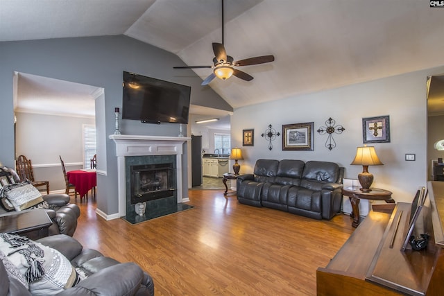 living area featuring a wealth of natural light, a tile fireplace, light wood-style flooring, and a ceiling fan