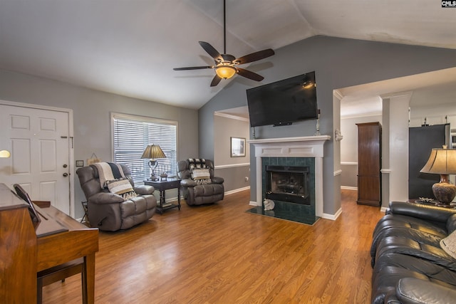 living room featuring lofted ceiling, ceiling fan, a tile fireplace, baseboards, and light wood-style floors