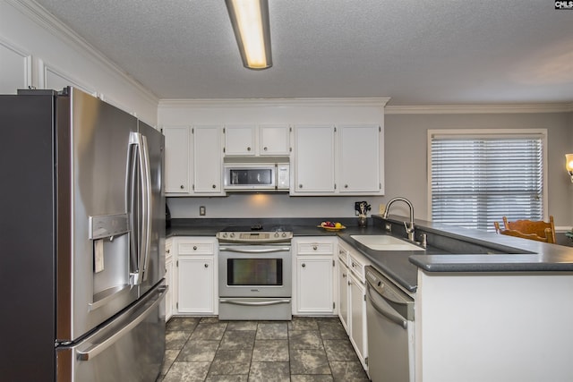 kitchen with dark countertops, appliances with stainless steel finishes, white cabinets, and a sink
