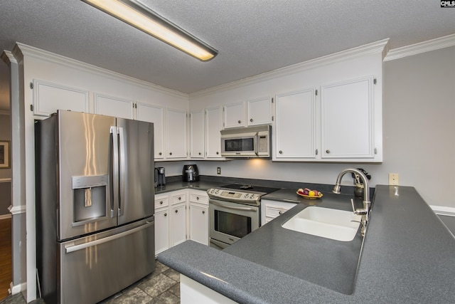 kitchen with dark countertops, ornamental molding, stainless steel appliances, white cabinetry, and a sink