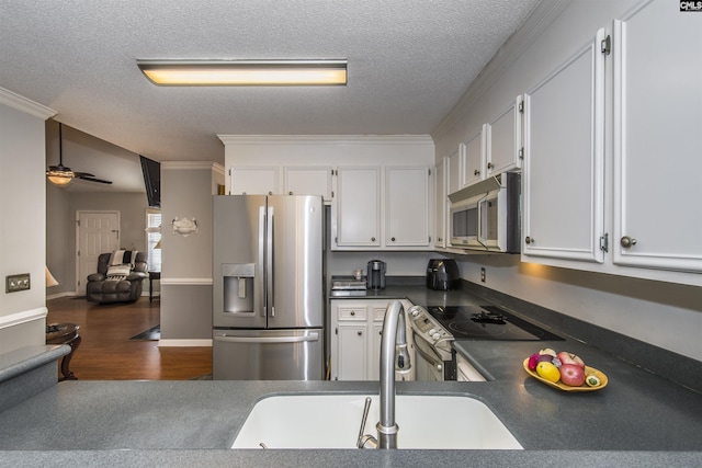 kitchen with a textured ceiling, stainless steel appliances, dark countertops, and white cabinets