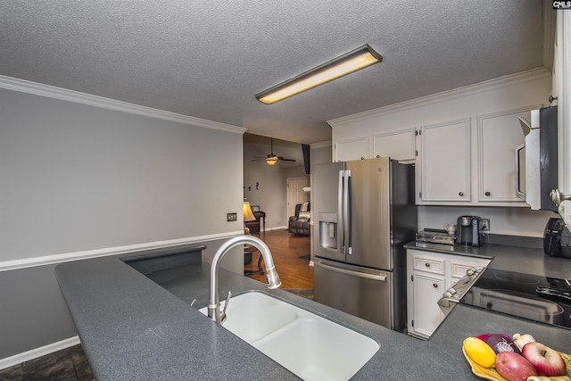 kitchen featuring stainless steel appliances, a sink, white cabinetry, dark countertops, and crown molding
