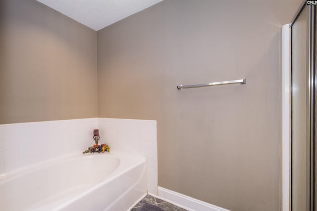 bathroom featuring a textured ceiling, a garden tub, and baseboards