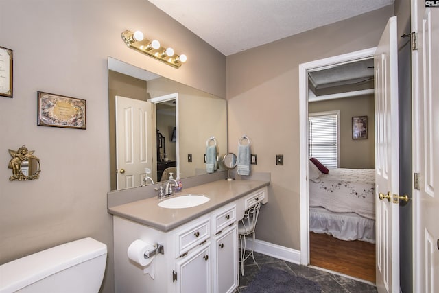 ensuite bathroom with toilet, ensuite bath, vanity, and baseboards