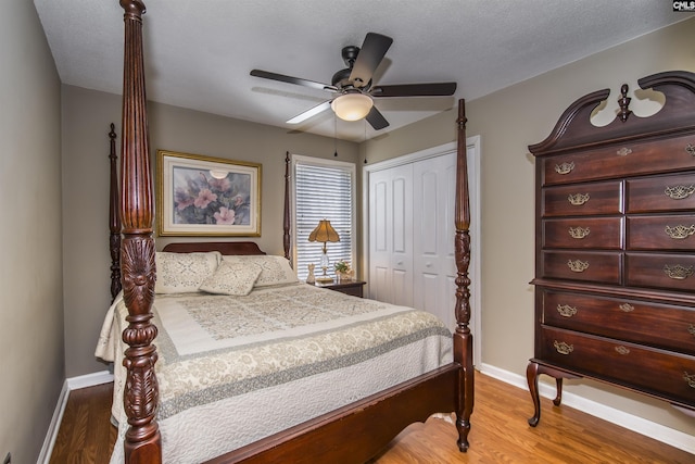 bedroom with a textured ceiling, wood finished floors, a ceiling fan, baseboards, and a closet