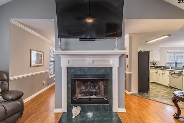 living room with light wood finished floors, ornamental molding, a fireplace, and baseboards
