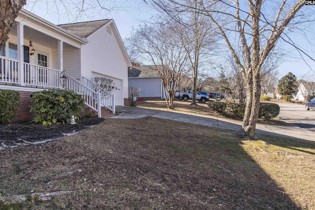 view of yard with covered porch, concrete driveway, stairs, and a garage