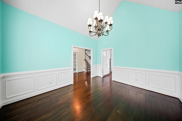 dining space with an inviting chandelier, dark wood-style floors, vaulted ceiling, and a wainscoted wall