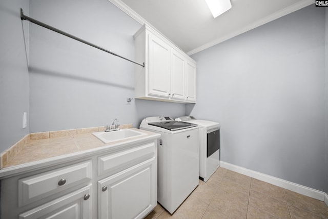 laundry area featuring crown molding, washing machine and clothes dryer, cabinet space, a sink, and baseboards