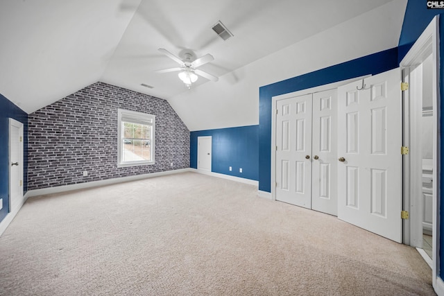 additional living space featuring lofted ceiling, brick wall, carpet, and a ceiling fan