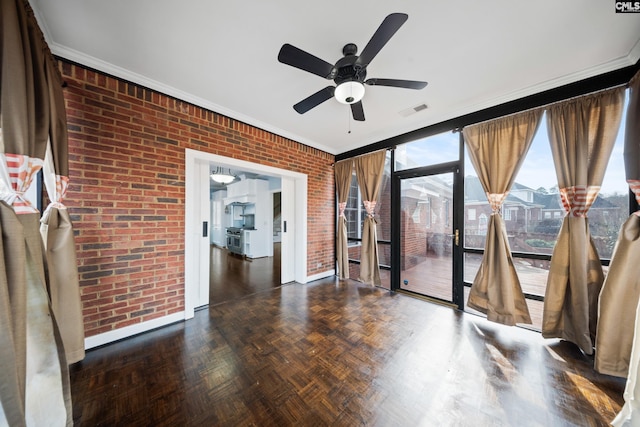 empty room featuring visible vents, a ceiling fan, a sunroom, brick wall, and ornamental molding