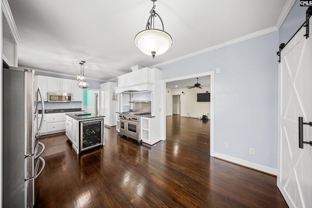 kitchen featuring ornamental molding, a barn door, dark wood-type flooring, and appliances with stainless steel finishes