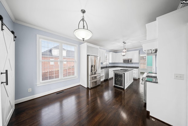 kitchen with a barn door, visible vents, dark countertops, dark wood-style floors, and appliances with stainless steel finishes