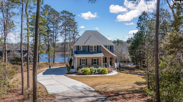 view of front of home with concrete driveway, a front lawn, and a water view