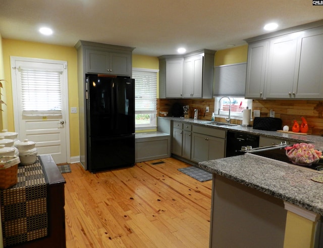 kitchen with gray cabinets, a sink, light wood-style flooring, and black appliances