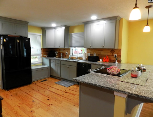 kitchen featuring a peninsula, black appliances, and a sink