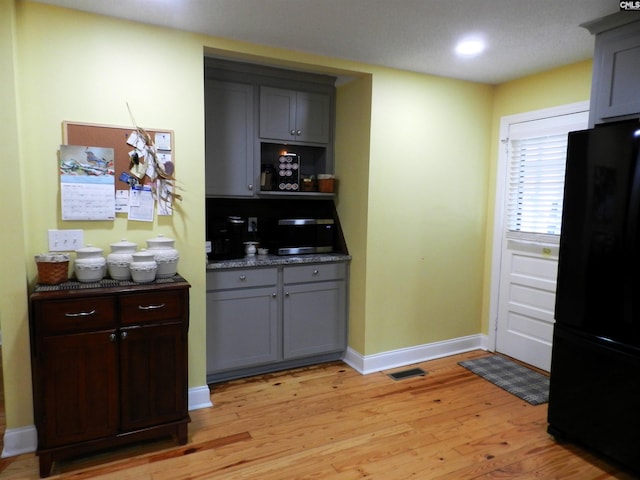 kitchen with dark countertops, light wood-style flooring, gray cabinets, and freestanding refrigerator