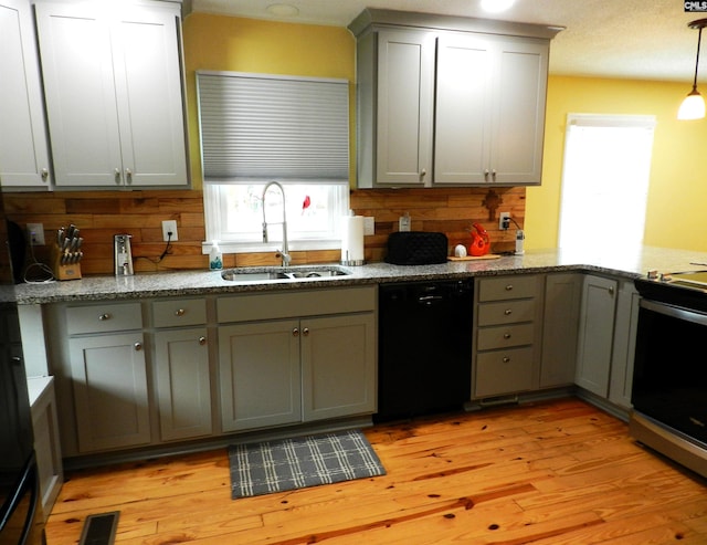 kitchen with light wood finished floors, visible vents, dishwasher, stainless steel stove, and a sink