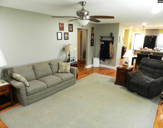 living area with ceiling fan, wood finished floors, and baseboards