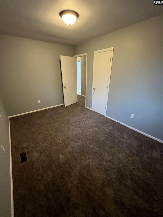 spare room with dark carpet and baseboards