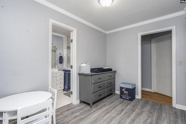 bedroom with a textured ceiling, baseboards, light wood-style flooring, and crown molding