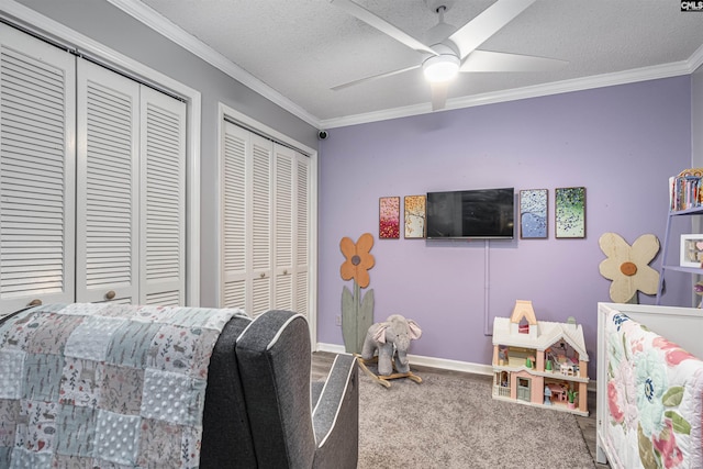 carpeted bedroom featuring ornamental molding, a textured ceiling, baseboards, and two closets