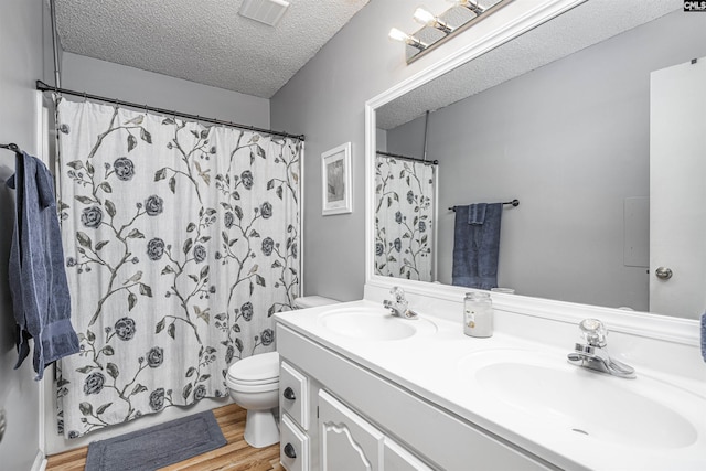 bathroom featuring a textured ceiling, wood finished floors, a sink, and visible vents