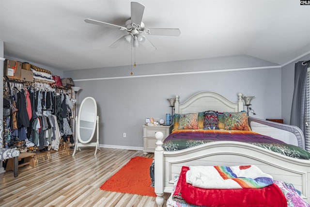 bedroom featuring light wood-type flooring, baseboards, vaulted ceiling, and a ceiling fan