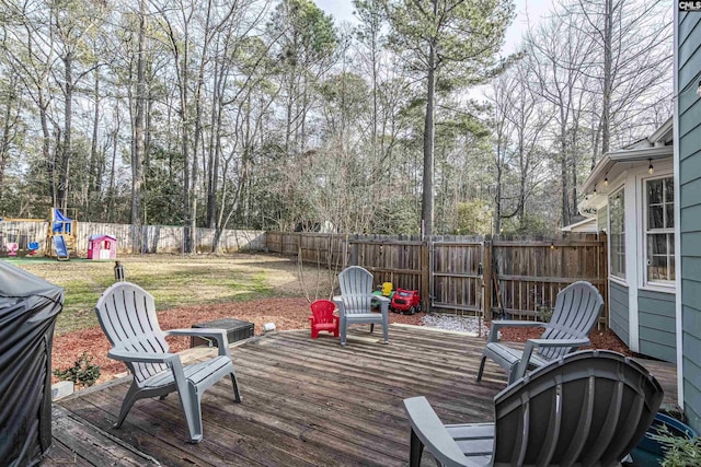 wooden deck with a fenced backyard, a lawn, and a playground