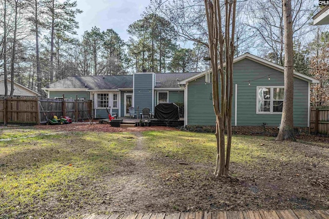 rear view of house featuring crawl space, a chimney, fence, and a lawn