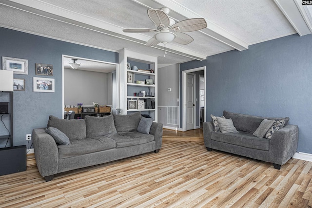 living room featuring light wood-type flooring, beam ceiling, and a textured ceiling