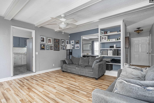 living room featuring ceiling fan, beamed ceiling, wood finished floors, and a textured ceiling