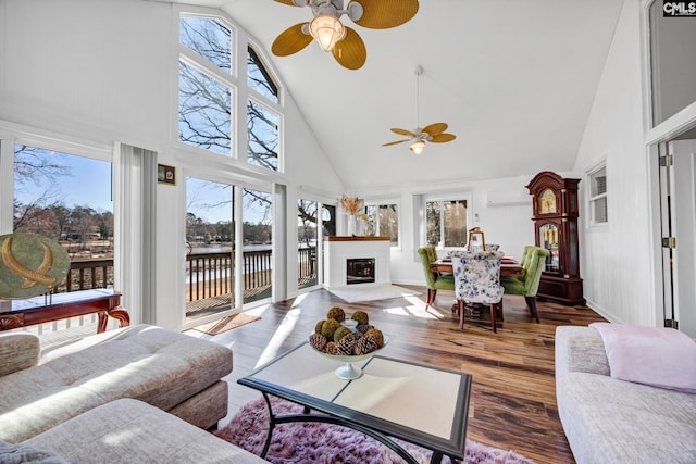 sunroom with a water view, a glass covered fireplace, a wealth of natural light, and a ceiling fan