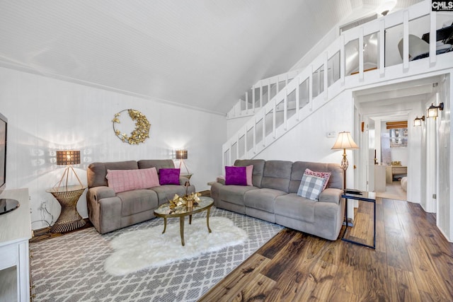 living room featuring stairs, vaulted ceiling, and wood finished floors